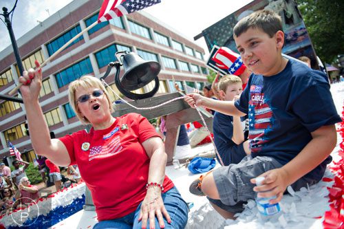 Caleb Johnson (right) rings a liberty bell while his grandmother Janet Johnson waves an American flag as they ride a float towards Historic Marietta Square during the city's  Freedom Parade on Friday, July 4, 2014. 