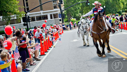 Betty Gottberg waves to the crowd as she rides her horse Martini towards Historic Marietta Square during the city's  Freedom Parade on Friday, July 4, 2014. 