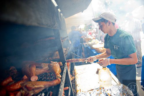Jose Valada turns over barbeque in a smoker in  Historic Marietta Square during the city's  Fourth in the Park celebration on Friday, July 4, 2014. 