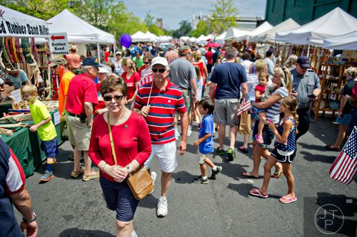 Jan Colpo (left) and her husband John make their way through the craft fair off of  Historic Marietta Square during the city's  Fourth in the Park celebration on Friday, July 4, 2014. 