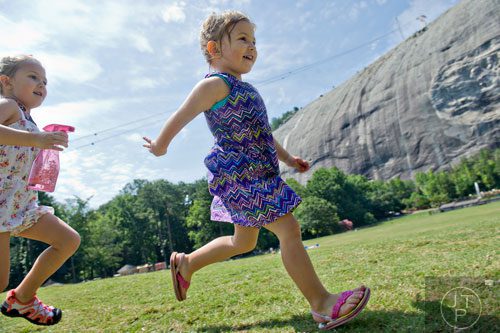 Gabraila Bartlett (left) chases after her sister Caroline with a water bottle on the main lawn at Stone Mountain Park during the Fantastic Fourth celebration weekend on Saturday, July 5, 2014.  