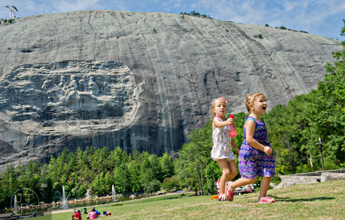 Gabraila Bartlett (left) chases after her sister Caroline with a water bottle on the main lawn at Stone Mountain Park during the Fantastic Fourth celebration weekend on Saturday, July 5, 2014.  