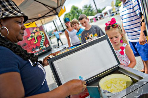 Teresa Davis-Howard (left) hands a spoonful of blueberry Italian ice to Madison Spillers (right) as her family peruses the food options during the Atlanta Food Festival at Jim R. Miller Park in Marietta on Sunday, July 6, 2014. 
