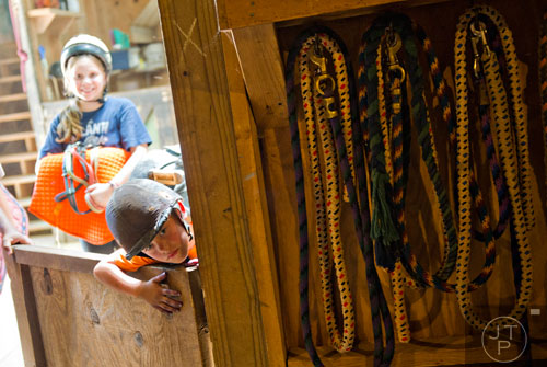 Matthew Ford peaks into the equipment stall during horseback riding summer camp at the Ellenwood Equestrian Center in Ellenwood on Wednesday, July 9, 2014.   