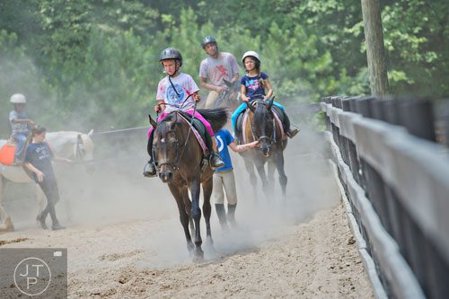 Sydney Spoeth (center) warms up her horse before going on a trail ride during horseback riding summer camp at the Ellenwood Equestrian Center in Ellenwood on Wednesday, July 9, 2014.  