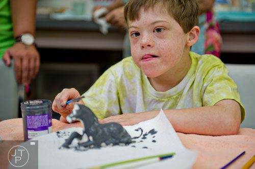 Tucker Rowlett paints a piece of pottery during Camp Happy Hearts in Alpharetta on Tuesday, June 17, 2014.