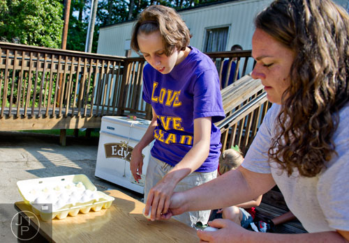 Morgan Ware (left) picks which egg to crack on Elinore Trotter's (not pictured) head with the help of teacher Carrie Shottenkirk during Mad Scientist Week at the Special Needs Schools of Gwinnett Summer Enrichment Camp in Lawrenceville on Wednesday, June 18, 2014.