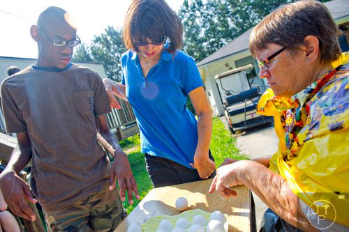 Jhazz Williams (left) picks which egg to crack on Elinore Trotter's (right) head with the help of teacher Rachel Moscoso during Mad Scientist Week at the Special Needs Schools of Gwinnett Summer Enrichment Camp in Lawrenceville on Wednesday, June 18, 2014. 