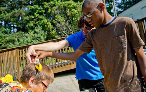 Jhazz Williams (right) cracks an egg on Elinore Trotter's head with the help of teacher Rachel Moscoso during Mad Scientist Week at the Special Needs Schools of Gwinnett Summer Enrichment Camp in Lawrenceville on Wednesday, June 18, 2014. 