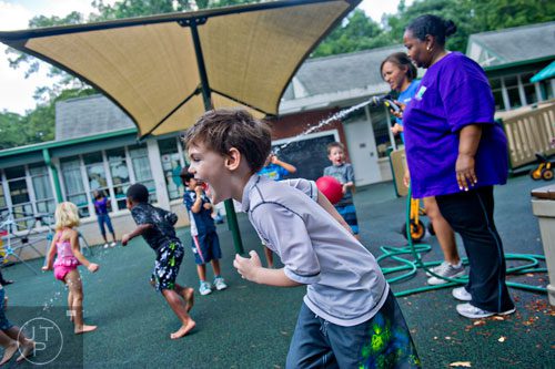 William Gutherie (center) and other campers scatter as LeTanya McKan uses a hose to cool them off during summer camp at the Frazer Center in Atlanta on Thursday, June 19, 2014. 