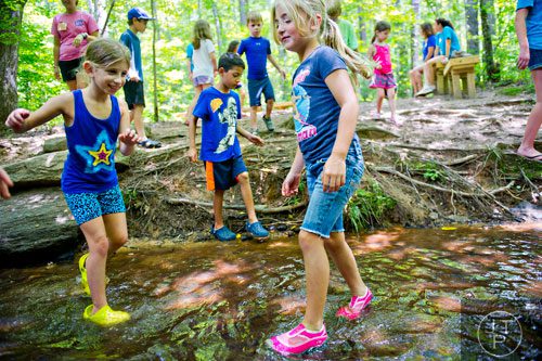 Almog Horowitz (left) and Addison Pancake (right) traverse the rocks in Sam's Creek during summer camp at Autrey Mill Nature Preserve in Johns Creek on Monday, July 14, 2014. 