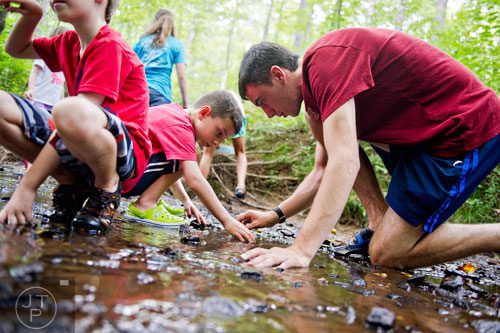 Carter Percy (right) helps Max Lint look for salamanders in Sam's Creek during summer camp at Autrey Mill Nature Preserve in Johns Creek on Monday, July 14, 2014.  