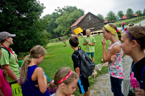 Nathan Hoffman (center) holds a sign as he waits for his group of campers to arrive during Camp Serenbe in Chattahoochee Hills on Tuesday, July 15, 2014. 