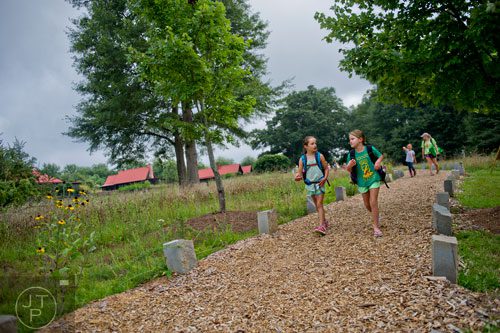 Kaitlyn Smith (left) and Liliana Fosdick talk as they walk the trail down to Camp Serenbe in Chattahoochee Hills on Tuesday, July 15, 2014.  