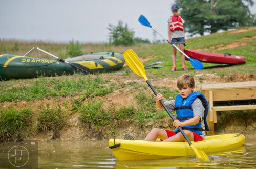 Mac Massie (left) paddles a kayak away from the dock as Juliet Joyce waits for her turn to put in during Camp Serenbe in Chattahoochee Hills on Tuesday, July 15, 2014.  