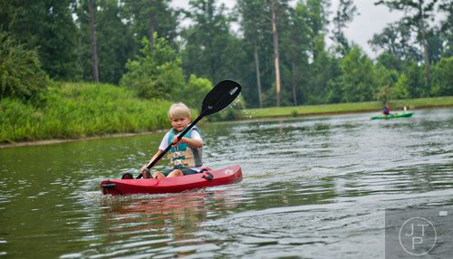 Nicholas Sanders (left) paddles a kayak along the water during Camp Serenbe in Chattahoochee Hills on Tuesday, July 15, 2014.   