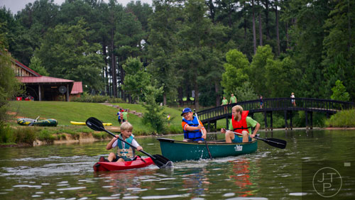 Nicholas Sanders (left) paddles a kayak along the water as he is chased by Aidan Kotheimer and Nathan Hoffman during Camp Serenbe in Chattahoochee Hills on Tuesday, July 15, 2014.   