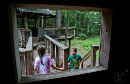 Liliana Fosdick (right) climbs the steps to the top of a tree house during Camp Serenbe in Chattahoochee Hills on Tuesday, July 15, 2014.  