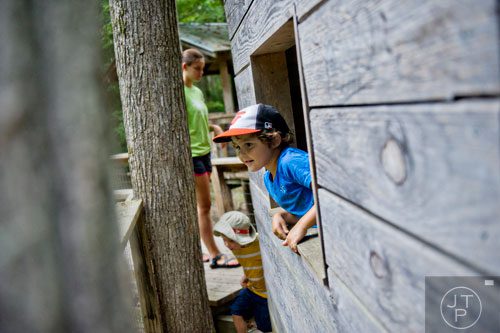 Lucas Ringstrom (center) pokes his head out of a window of a tree house during Camp Serenbe in Chattahoochee Hills on Tuesday, July 15, 2014.  