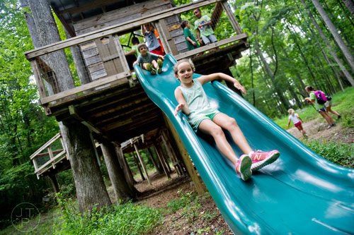 Kaitlyn Smith (center) shoots down a slide from the top of a tree house during Camp Serenbe in Chattahoochee Hills on Tuesday, July 15, 2014.  