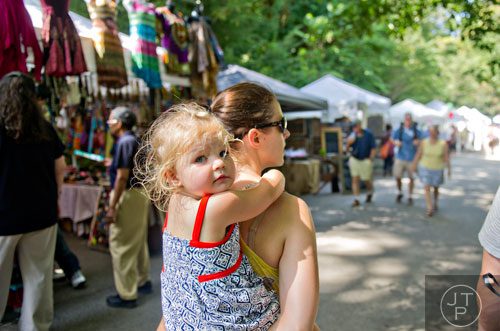 Mavis Butcher (left) rides on her mother Emily's back as they pass artist booths during the Grant Park Summer Shade Festival in Atlanta on Saturday, August 23, 2014. 