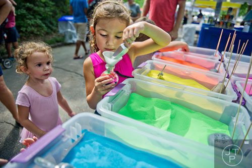 Lila Teras (left) watches her sister Sadie fill a glass bottle with colored sand during the Grant Park Summer Shade Festival in Atlanta on Saturday, August 23, 2014. 