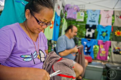 Sawai McLaughlin (left) and her husband George cut out material on shirts during the Grant Park Summer Shade Festival in Atlanta on Saturday, August 23, 2014. 