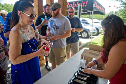 Nicole Little (left) holds onto her glass as she waits for change from Elyse Moore at Red Hare Brewery in Marietta during the company's third anniversary party on Saturday, August 23, 2014. 