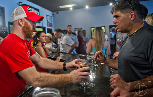 Stephen Upchurch (left) hands Tommy Vicente glasses full of beer at Red Hare Brewery in Marietta during the company's third anniversary party on Saturday, August 23, 2014. 