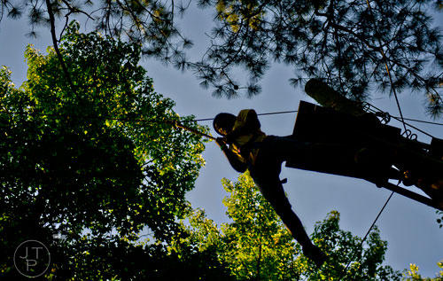Armalin Greene launches herself off of a zip line platform at Camp Timber Ridge in Mableton on Thursday, July 17, 2014.  