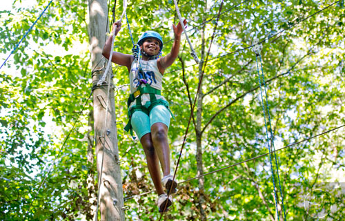 Shelby Mullen makes her way across a wire on the high ropes course at Camp Timber Ridge in Mableton on Thursday, July 17, 2014.  