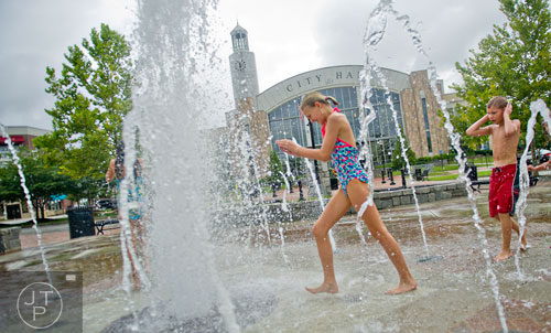 Catherine Howard (left) and her brother Thomas run through the fountain at Town Center Park in Suwanee on Tuesday, July 22, 2014.  