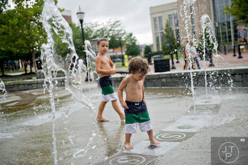 Landon Corney (right) and his brother Logan play in the fountain at Town Center Park in Suwanee on Tuesday, July 22, 2014.   