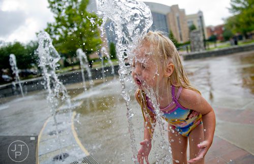 Jane Sloan sticks her face in one of the spouts of the fountain at Town Center Park in Suwanee on Tuesday, July 22, 2014. 