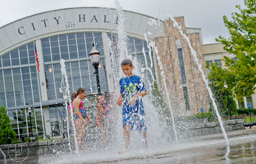 Dante Miller (center) runs through the fountain at Town Center Park in Suwanee on Tuesday, July 22, 2014.