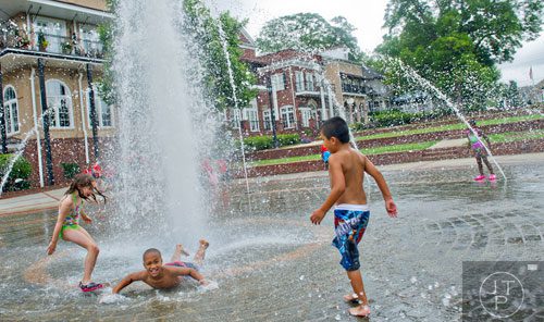 Addison Schulz (left), Temerian Gresham and Josue Almaraz play in the fountain at the Duluth Town Green on Tuesday, July 22, 2014. 