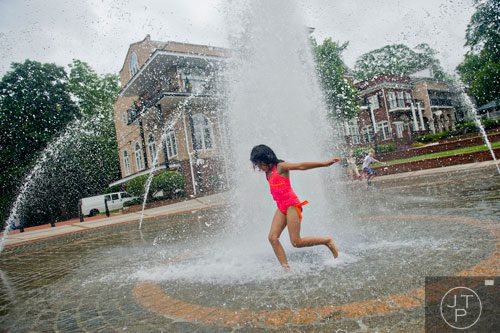 Isabella Garcia (center) runs through the fountain at the Duluth Town Green on Tuesday, July 22, 2014.  