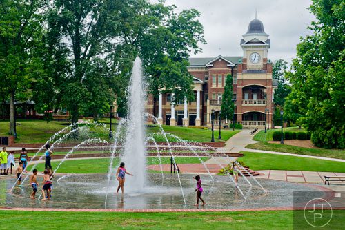 Children play in the fountain at the Duluth Town Green on Tuesday, July 22, 2014.