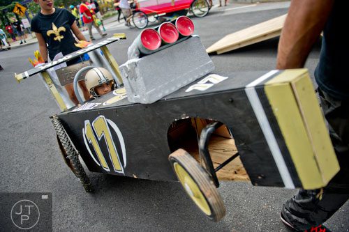 Brennon Jones (center) sits in his vehicle as he is pulled to the starting line for the 2nd annual Cool Dads Rock Soap Box Derby at Historic Fourth Ward Park in Atlanta on Saturday, August 2, 2014. 