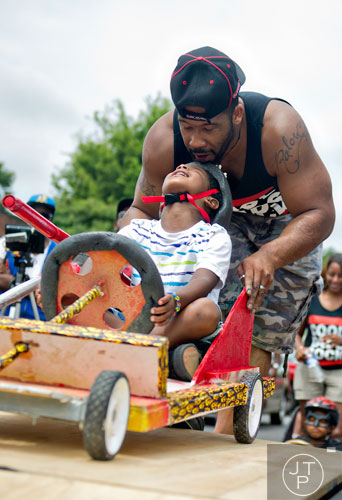 Jojo Stancil (front) looks up at his father Jerome as he prepares to take off from the starting line for the 2nd annual Cool Dads Rock Soap Box Derby at Historic Fourth Ward Park in Atlanta on Saturday, August 2, 2014.