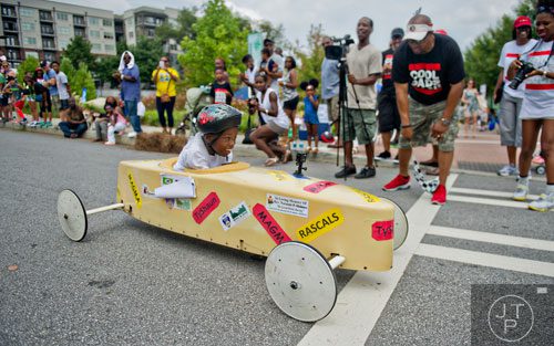 Tyshaun Johnson (center) crosses the finish line during the 2nd annual Cool Dads Rock Soap Box Derby at Historic Fourth Ward Park in Atlanta on Saturday, August 2, 2014.