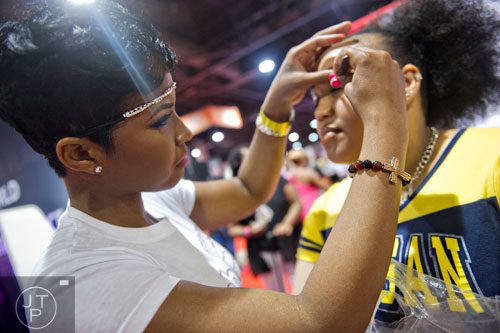 Joyua Gibson (left) applies lashes to Kanisha Brewer's eyelids during the International Bronner Bros. Hair Show at the Georgia World Congress Center in Atlanta on Saturday, August 2, 2014.