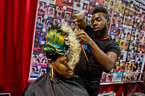 Michelle Brown (center) sits in a chair as Dominique Holloway works on her hair during the International Bronner Bros. Hair Show at the Georgia World Congress Center in Atlanta on Saturday, August 2, 2014. 