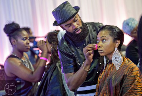 Christian Balenciaga (center) applies makeup to Kash Howard's face as he participates in the makeup competition during the International Bronner Bros. Hair Show at the Georgia World Congress Center in Atlanta on Saturday, August 2, 2014. 