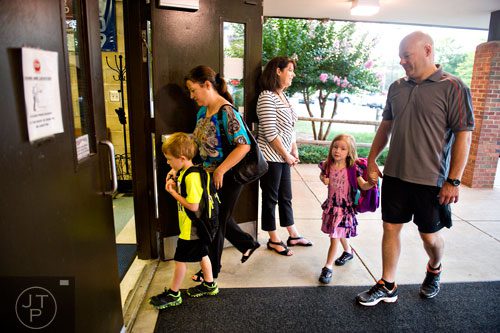 Wayne Williams (right) holds his daughter Nicole's hand while his wife Kerry walks with their son Trevor as they pass by Kelly Llerandi (center) for the first day of classes at Davis Elementary School in Marietta on Monday, August 4, 2014. 