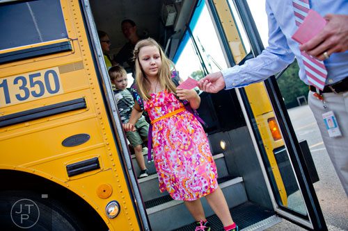 Selah Christopher (center) is handed a notecard as she steps off the bus with her brother Elijah at Davis Elementary School in Marietta on Monday, August 4, 2014.