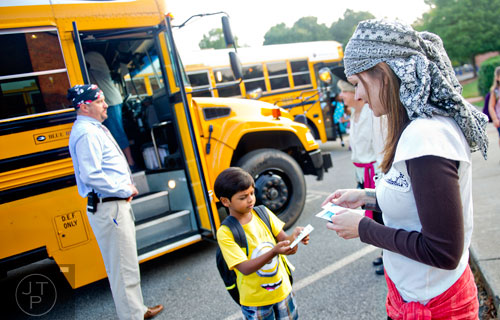 Nora Sanders (right) hands Viraj Sheel a notecard as he steps off the bus at Davis Elementary School in Marietta on Monday, August 4, 2014. 