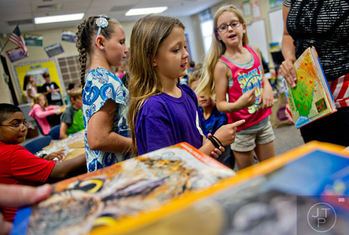 Reese Hoggard (center), Emma Rose and Grace Holmes receive their text books on the first day of school at Davis Elementary School in Marietta on Monday, August 4, 2014. 