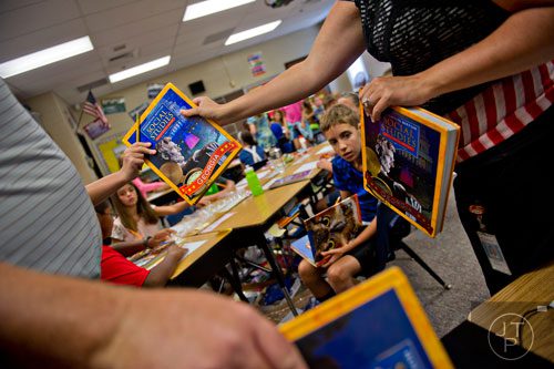 Melissa Bujnoch (right) hands out text books to her fifth graders at Davis Elementary School in Marietta on Monday, August 4, 2014. 
