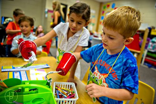 Charlie Latzak (right) and Gaby Farah reach for art supplies with hooked hands during the first day of school at Davis Elementary School in Marietta on Monday, August 4, 2014. 